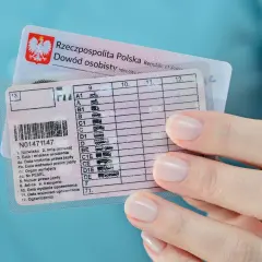 Dłoń trzyma polskie prawo jazdy kategorii B i dowód osobisty. Dokumenty są gotowe do podróży.