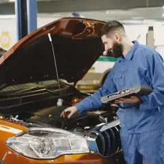Mechanik z komputerem diagnostycznym sprawdza silnik. Zastanawiasz się, ile trwa wymiana oleju? To szybka usługa!