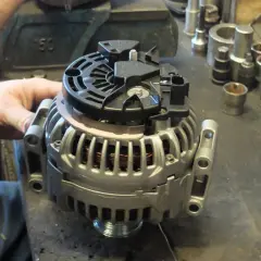 Warsztat samochodowy. Mechanik pracuje nad regeneracją alternatora. Sprawdź, jaka jest regeneracja alternatora cena.