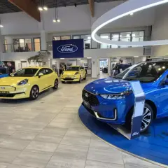 Salon Forda z niebieskim i żółtym autem. Zastanawiasz się, leasing co to? To sposób na posiadanie nowego auta bez wysokiego wkładu własnego.