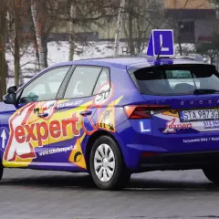 Niebieski samochód szkoleniowy z napisem "Expert" i literą "L" na dachu. Idealny do nauki jazdy, by zdobyć prawo jazdy 17 lat.