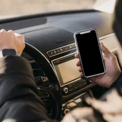 Kierowca trzyma telefon, zastanawiając się, ile punktów za telefon straci.
