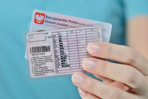 Dłoń trzyma polskie prawo jazdy kategorii B i dowód osobisty. Dokumenty są gotowe do podróży.