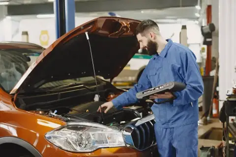 Mechanik z komputerem diagnostycznym sprawdza silnik. Zastanawiasz się, ile trwa wymiana oleju? To szybka usługa!