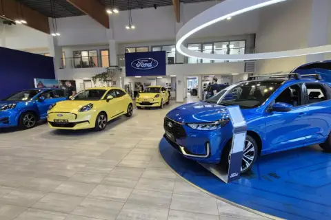Salon Forda z niebieskim i żółtym autem. Zastanawiasz się, leasing co to? To sposób na posiadanie nowego auta bez wysokiego wkładu własnego.