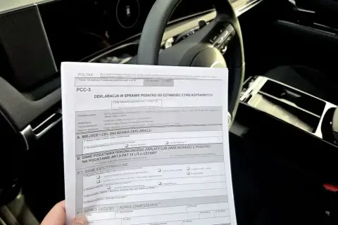 Formularz PCC-3 do rozliczenia podatku od zakupu samochodu. Wypełniony dokument leży na siedzeniu auta.