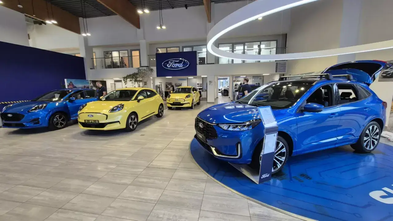 Salon Forda z niebieskim i żółtym autem. Zastanawiasz się, leasing co to? To sposób na posiadanie nowego auta bez wysokiego wkładu własnego.
