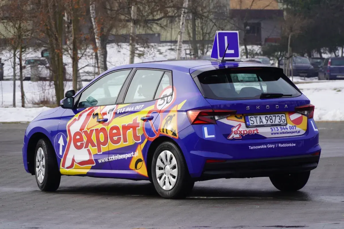 Niebieski samochód szkoleniowy z napisem "Expert" i literą "L" na dachu. Idealny do nauki jazdy, by zdobyć prawo jazdy 17 lat.
